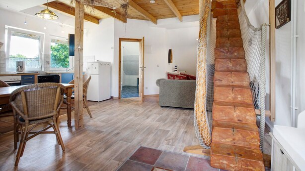 Une cuisine spacieuse avec un plancher en bois, un coin repas avec des chaises en osier et un escalier au design rustique.