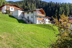 Un immeuble à plusieurs étages, doté d’une façade blanche, de balcons en bois et d’un escalier menant à l’entrée.