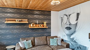 A modern living room with a brown sectional sofa, a small round table, and a large wall mural. - Holiday Apartment 'Quiet Basement Apartment with Terrace' with Private Terrace, Garden, and Wi-Fi (Altenkunstadt)
