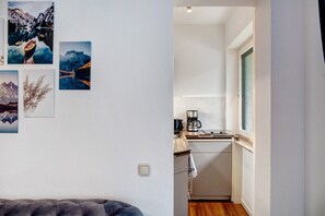 Un espacio habitable compacto con kitchenette, una cama y una pared decorada con fotografías de paisajes.
