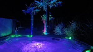 A hot tub with colorful lights and two palm trees. - Apartment 'Wohlfühloase Ermreuth' with Mountain View, Private Pool and Wi-Fi (Neunkirchen am Brand)