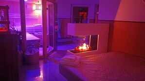 A room with a bed, a small fire feature, a wooden door, and a view of another room. - Apartment 'Wohlfühloase Ermreuth' with Mountain View, Private Pool and Wi-Fi (Neunkirchen am Brand)