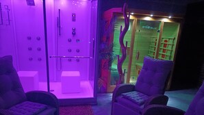 A spa area with a massage chair, a small table, and a shower area. - Apartment 'Wohlfühloase Ermreuth' with Mountain View, Private Pool and Wi-Fi (Neunkirchen am Brand)