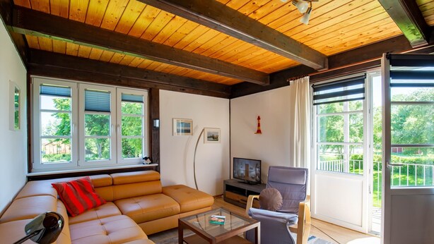 Een woonkamer met een bank, een glazen salontafel, een televisie en een fauteuil.