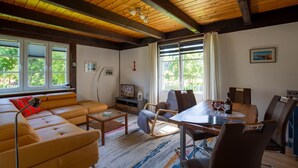 Een woonkamer met een bank, eettafel, stoelen en een televisie.