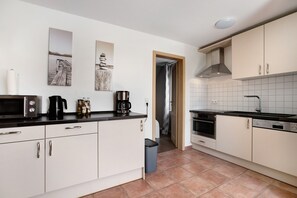 Una cocina moderna con armarios blancos, encimera negra y salpicadero de azulejos.
