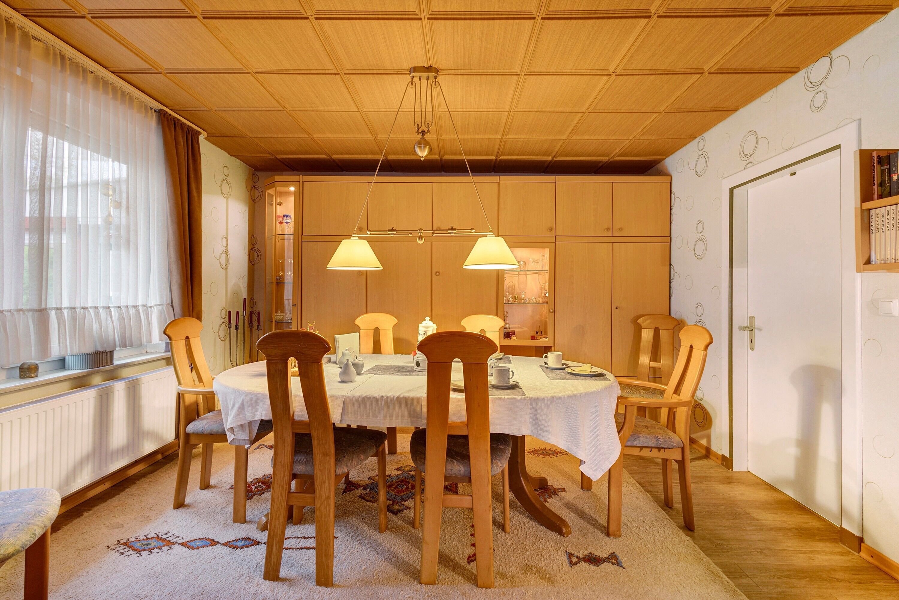 A dining area with a wooden table, chairs, and a chandelier.