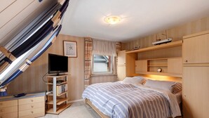 A bedroom with a bed, a TV, a desk, and a window. - Holiday Apartment 'Ferienhaus Marchlewski' with Shared Garden and Wi-Fi (Brunsbüttel)