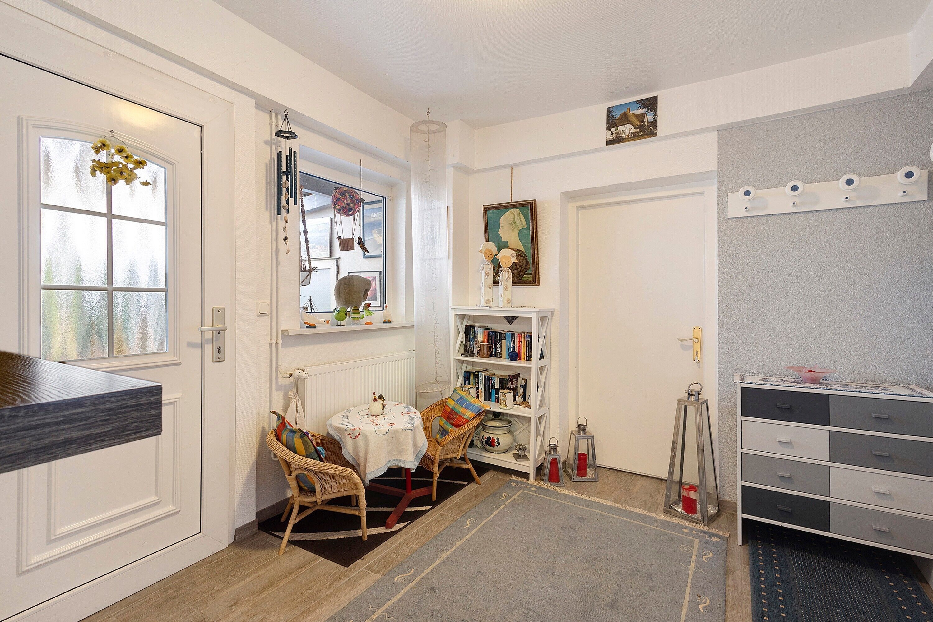 A room with a dining table, chairs, a bookshelf, a radiator, and a cabinet.
