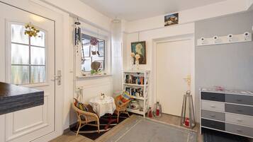 A room with a dining table, chairs, a bookshelf, a radiator, and a cabinet.