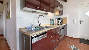 A modern kitchen with stainless steel appliances, wooden countertops, and a built-in dishwasher. - Apartment Müllerwohnung with Terrace (Pellworm)