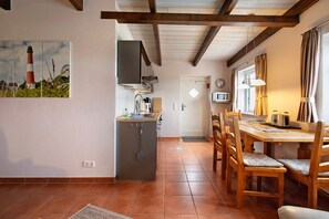 Una cocina con refrigerador, pileta y mesa de comedor de madera con sillas.
