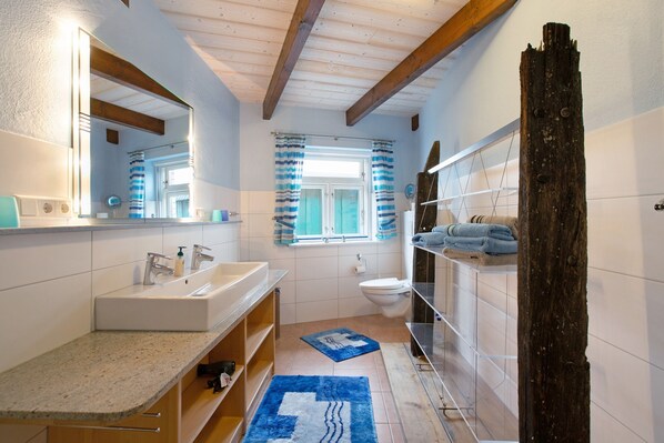 A bathroom with a sink, mirror, toilet, and shower curtain.