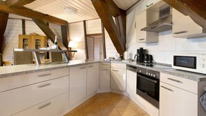 A kitchen with white cabinets, a built-in oven, a microwave, and a coffee maker. - Apartment Inselblick with Island Views (Pellworm)