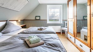 Et soveværelse med to senge, et vindue, et garderobeskab og en radiator.