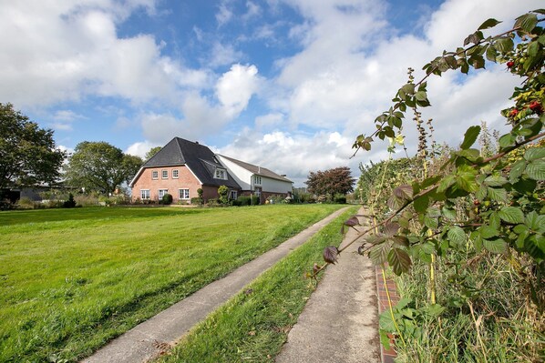 Une maison avec un toit en pente, un chemin pavé et une cour gazonnée.
