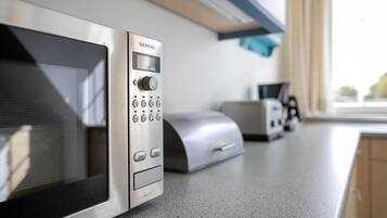 Une cuisine équipée d’un four à micro-ondes, d’un grille-pain et d’une fenêtre avec des rideaux.