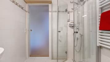 Un baño moderno con cabina de ducha de vidrio, un lavabo blanco y una toalla roja.