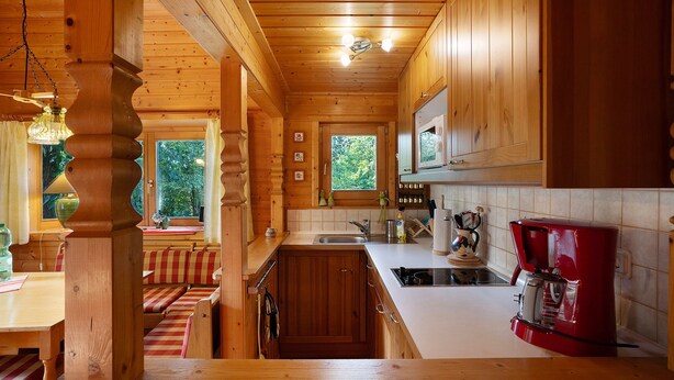 L’intérieur d’un chalet en bois comprend une cuisine, un coin repas et une fenêtre donnant sur la forêt.