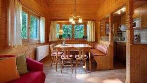 L’intérieur d’un chalet en bois comprend une table à manger, des chaises, un banc et un coin cuisine.