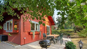 Une maison rouge avec un patio, un barbecue et du mobilier d’extérieur.