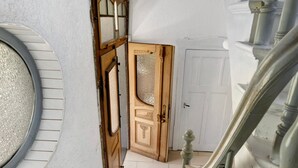 Una porta in legno con vetri, una parete bianca e una scala con ringhiera.