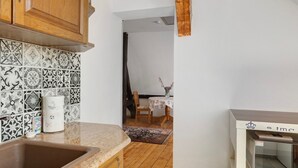 Una cucina con lavello, mobili in legno, piastrelle decorate, un forno a microonde e un'area pranzo con tavolo e sedia.