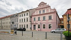Une rue bordée de bâtiments historiques, avec une chaussée pavée et des voitures garées.