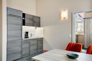 Una cocina moderna con armarios grises, una encimera blanca y una cafetera negra.