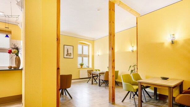 A room with yellow walls, a wooden-framed door, a dining table with chairs, and a window with blinds. - Apartment 'Ferienwohnung 3' with Shared Terrace and Wi-Fi (Luckau)