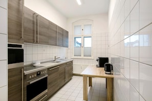 Eine moderne Küche mit Einbauofen, Kaffeemaschine und einem Fenster mit Jalousien.