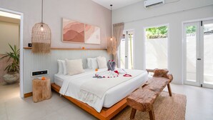 Un dormitorio moderno con una cama grande, un banco de madera y una lámpara colgante.