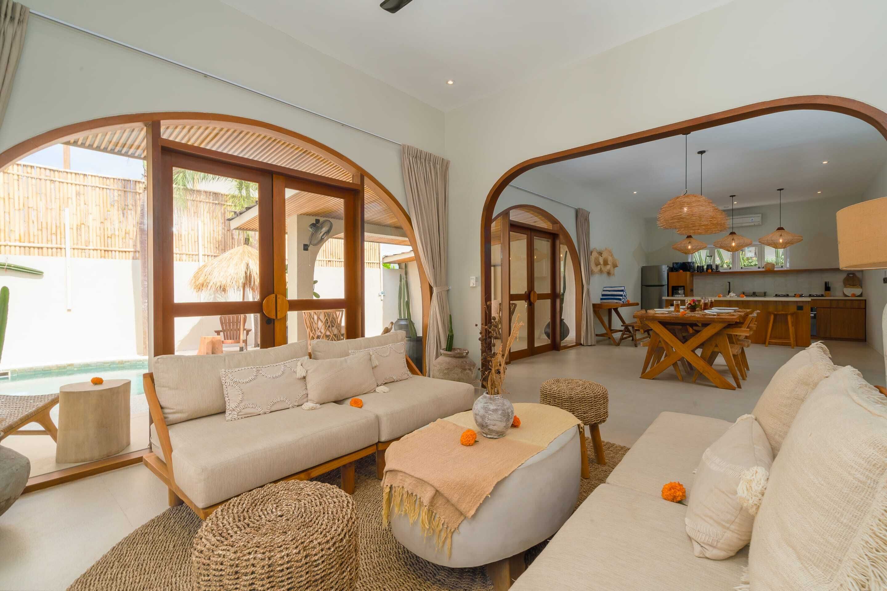 A spacious living area with a sofa, a dining table, and a kitchen in the background.