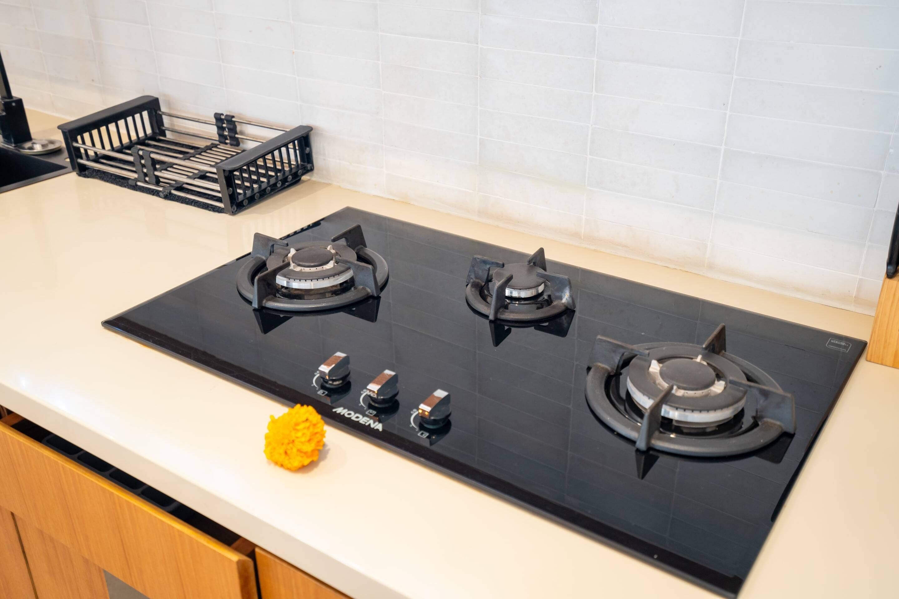 Una cocina con tope negro, cuatro hornillas y un panel de control.
