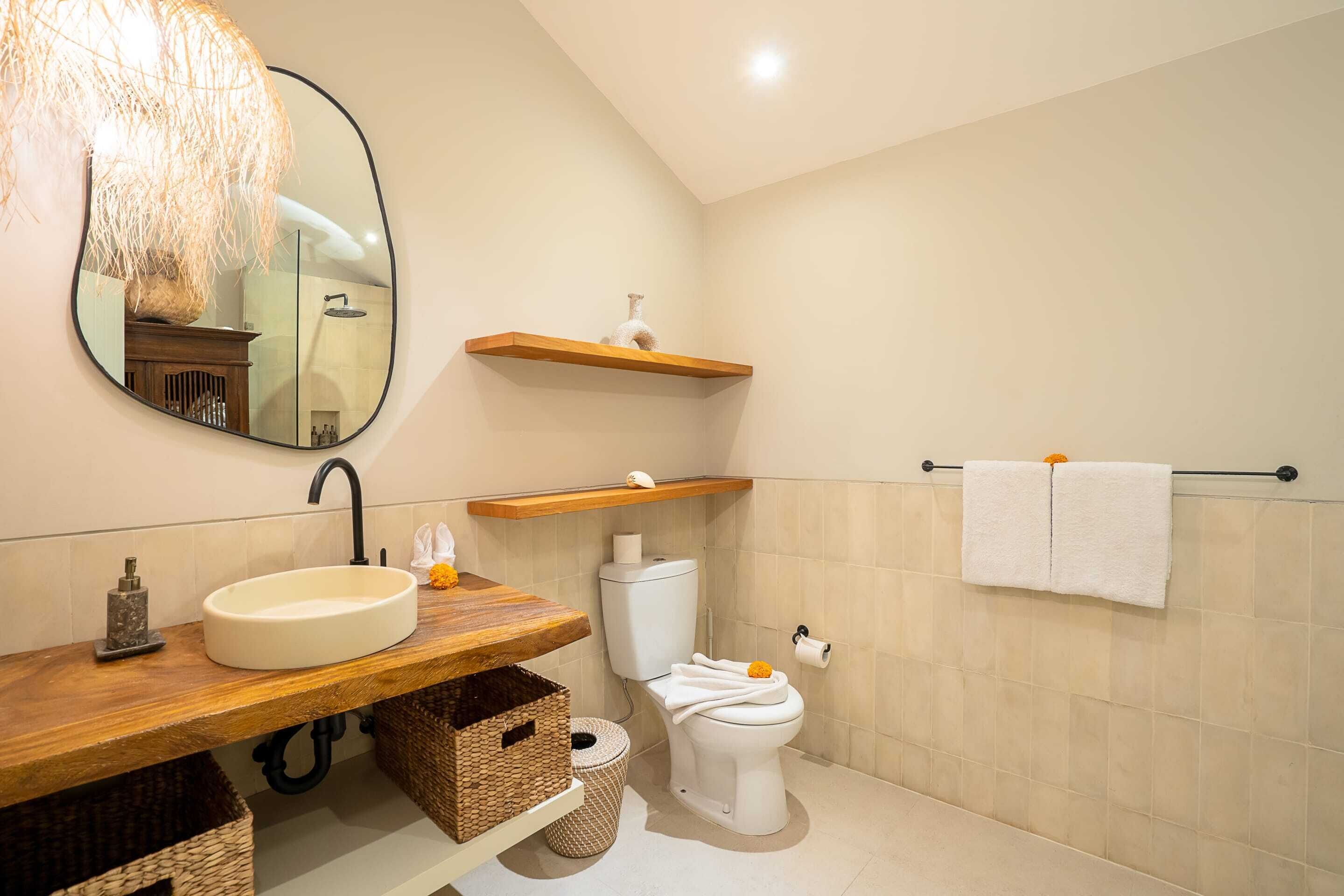 A bathroom with a wooden vanity, a round sink, a toilet, a towel rack, and a mirror.