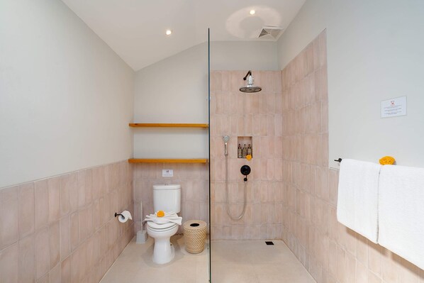 Un baño moderno con inodoro, ducha y perchero.