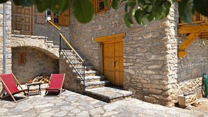 Un edificio de piedra con una puerta de madera, una escalera y sillones rojos.