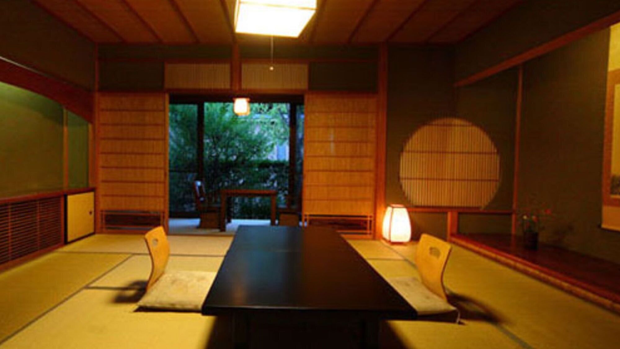 A traditional Japanese room with tatami flooring, a low table, and sliding doors leading to a garden.