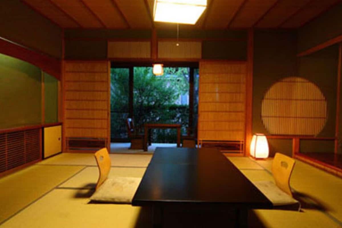 Una habitación japonesa tradicional con suelo de tatami, una mesa baja y puertas correderas que dan a un jardín.