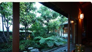 Ein traditioneller japanischer Garten mit einer Holzbeschaffenheit, einem Kiesweg und Blick auf üppiges Grün.