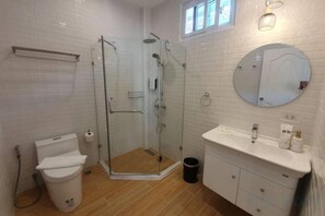 A bathroom with a glass-enclosed shower, a toilet, a sink with a mirror, and a trash bin. - Zenzen Pool Villa (San Sai)