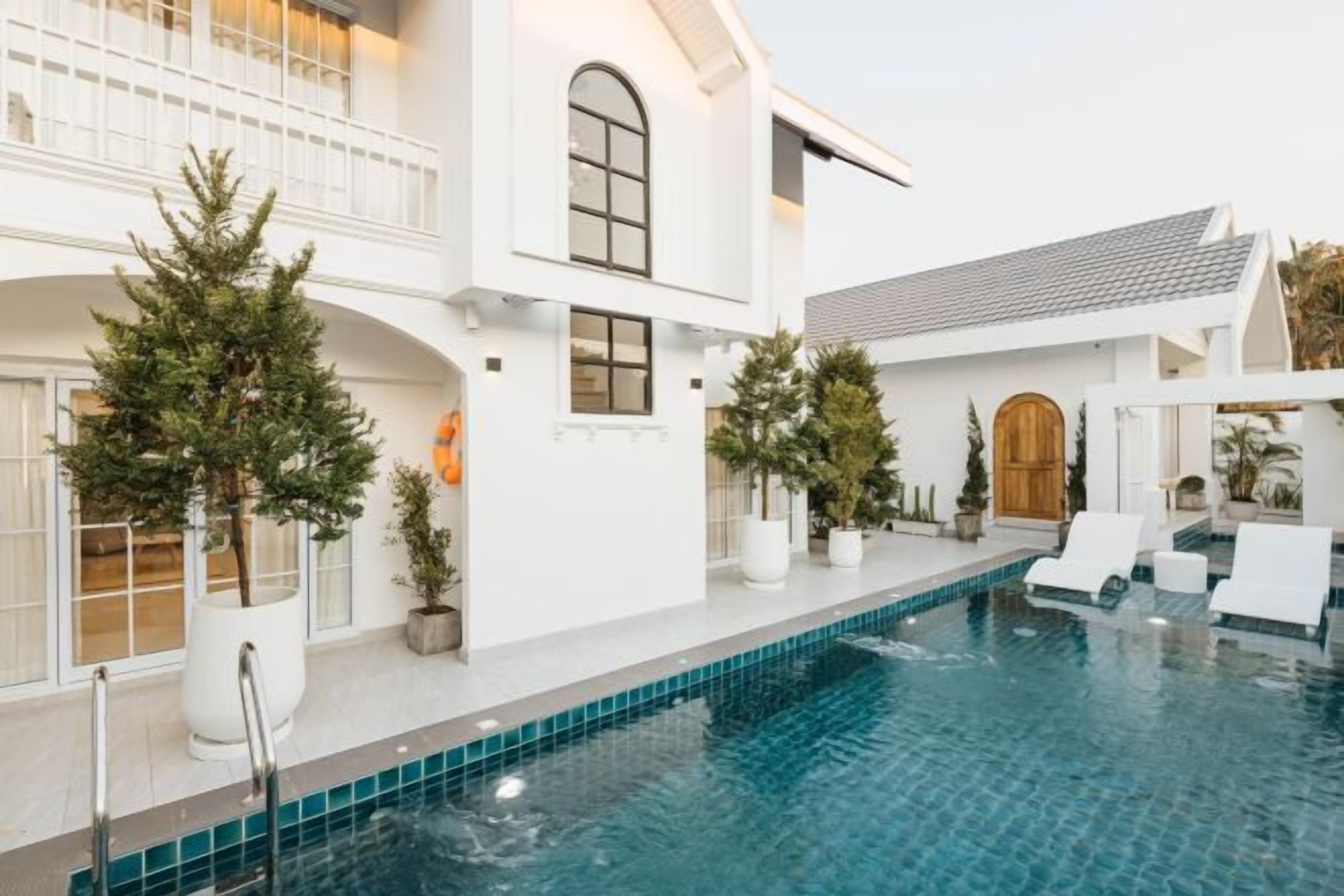 A modern house with a swimming pool, white exterior, and multiple windows.