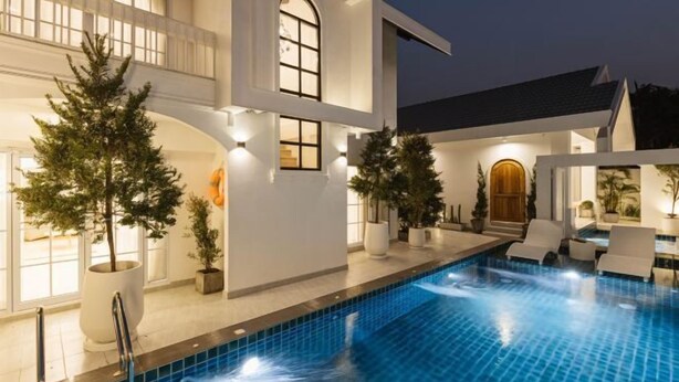 A modern house with a swimming pool, outdoor seating, and potted plants. - Zenzen Pool Villa (San Sai)