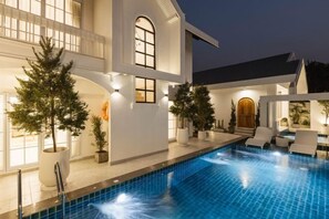 A modern house with a swimming pool, outdoor seating, and potted plants. - Zenzen Pool Villa (San Sai)