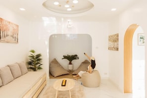 A modern living room with a sofa, bean bag, and a small table. - Zenzen Pool Villa (San Sai)