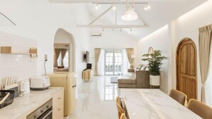 A modern kitchen with a marble countertop, a dining area with a large table, and a cozy seating area with a plant. - Zenzen Pool Villa (San Sai)