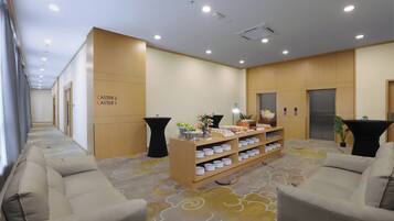 A reception area with a reception desk, two sofas, a coffee station, and a wall with directional signs.