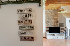 Pared con citas motivacionales y una sala de estar moderna con televisor, pared de piedra y techo de madera.