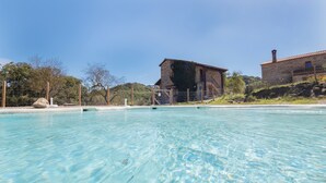 A clear pool with a stone building in the background. - Chalet 'Masia La Clariana' with Mountain Views, Private Pool and Wi-Fi (Castelltallat)