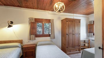Una habitación con dos camas, armario de madera y ventana con cortinas.